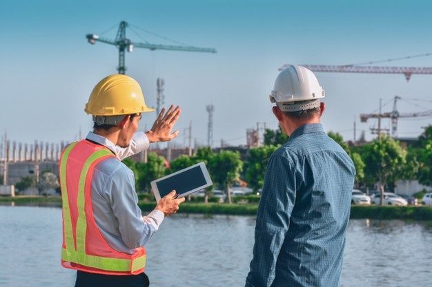 Premium Photo _ Two people worker engineer talking discussion by tablet on site building real estate construction
